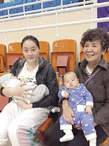 孙耀兰(图左)与李媚的妈妈抱着孩子坐在看台上观战